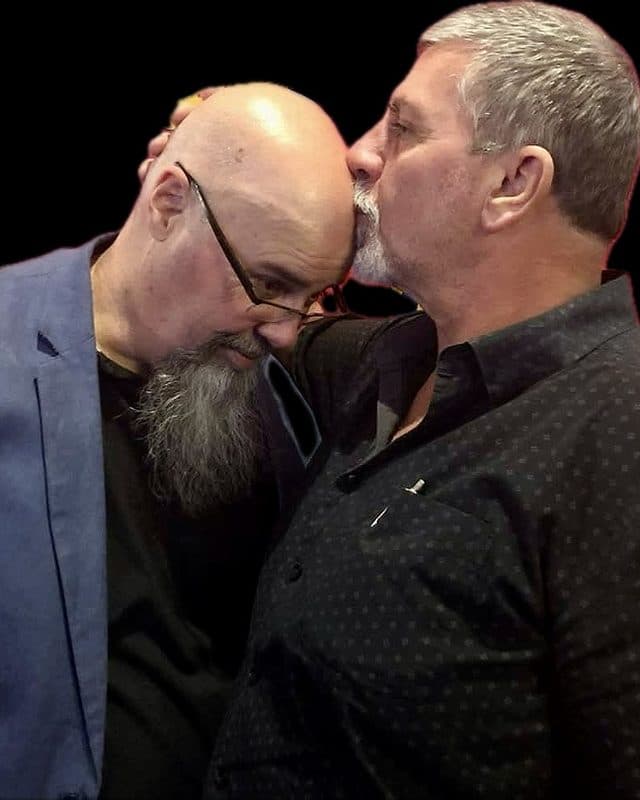 1 man in short sleeves (Damian Cosgriff) kissing the head of another man in a suit (Craig Coombes) with a caption below stating, "Tumour has it..."<br>Below that appear the words: "Two blokes. Two tumours. One very questionable sense of humour.<br>Yes, it involves tumours. No, it’s not a support group. You’re allowed to laugh."