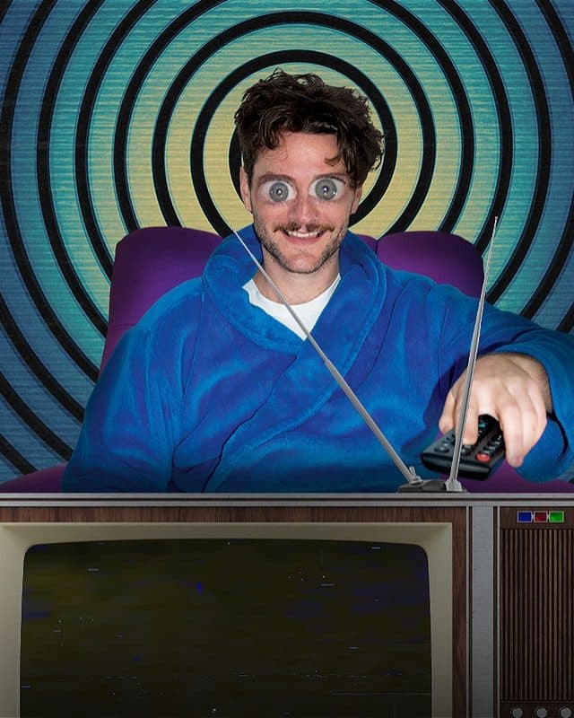The performer sits face on with a TV remote in hand staring at a TV set with comically enlarged eyes, as if in a trance watching the screen. He sits in front of a bright, swirling hypnotic background.